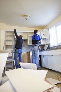 Two men tearing out old kitchen during home renovations.